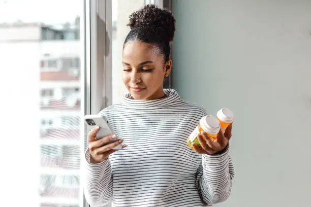 Woman authenticating medication by scanniing QR  code with smartphone.